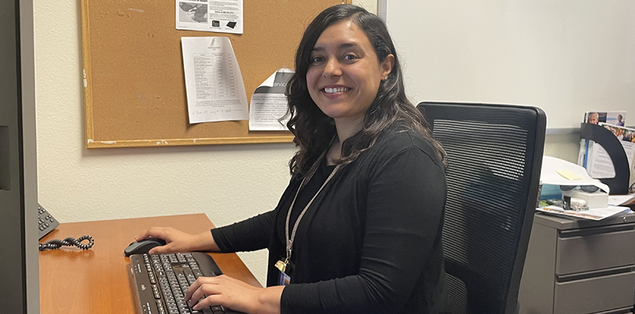 Photo of young woman sitting at her computer smiling